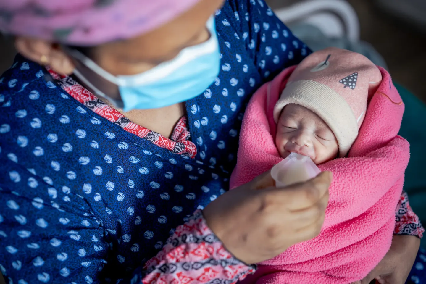 Mother feeding her newborn via cup feeding