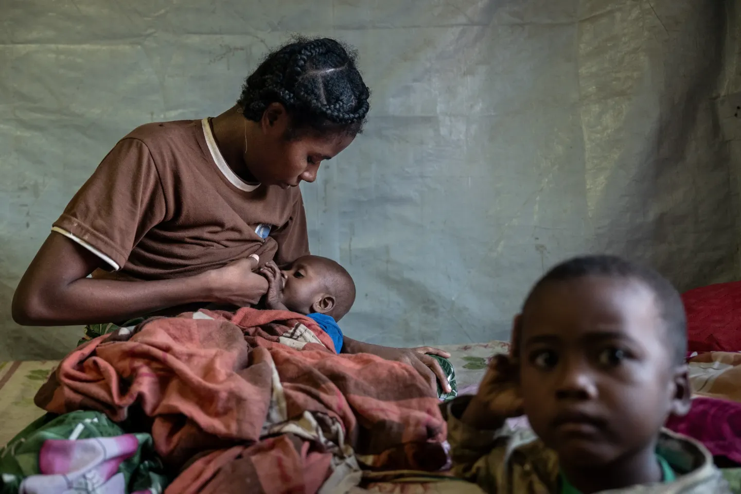 17 May 2025, at the Intensive Nutritional Recovery and Education Center (CRENI) of Ambovombe, Androy Region, Madagascar &mdash; Angel, 29, is seen breastfeeding her 17-month-old son, Tovonjay, while Tovonjay older brother, four-year-old Mario, looks toward the camera. Angel explains that Tovonjay has a tongue-tie, which makes feeding extremely difficult and is the main cause of his malnutrition.