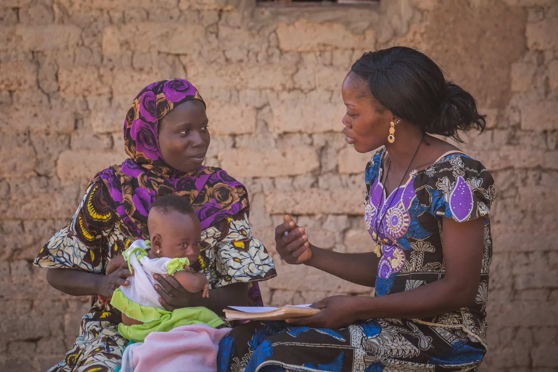 In the village of Ouisga, Passor&eacute; Province, Yako District, Burkina Faso, a woman holds her three-month-old, being coached by a community relay on the importance of exclusive breastfeeding.